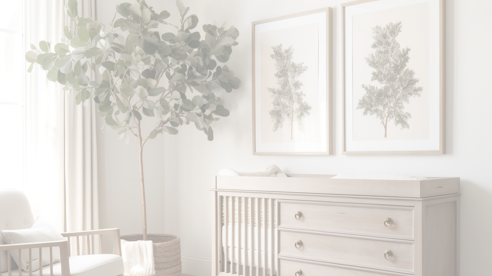 A picture of a child’s nursery. It shows a dresser with a changing table on top, with two huge frames that have one green tree and a light pink background in each one. They are located directly above the dresser. And in the corner, there is a tall green plant with a white rocking chair on its side.