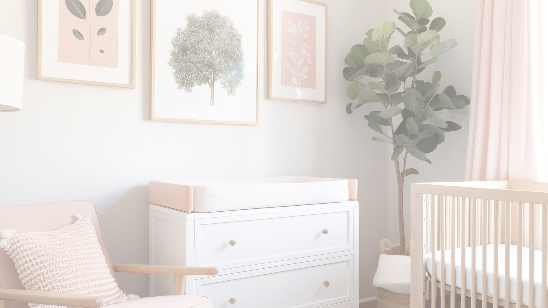 A picture of child's nursery. The picture shows a part of child's crib, with a green plant behind it, a white dresser with a changing table on top, a comfortable rocking chair, and three frames hung on the wall behind white dresser. The middle frame is the largest one, with a white background and a green tree in the center, the other two frames have both a pink and white backgrounds.