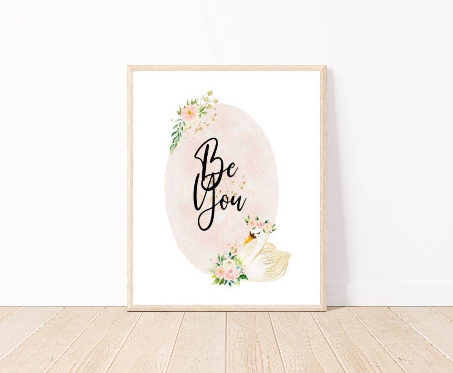 A digital graphic showing a baby pink oval shape decorated with flowers on the top and the bottom of the shape and beside the flowers at the bottom there is a cute goose illustration, with the phrase “Be You” written in black text inside the emblem.