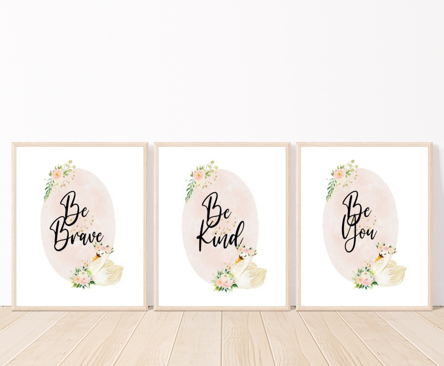 Three identical digital graphics but have different writings showing a baby pink oval shape decorated with flowers on the top and the bottom of the shape and beside the flowers at the bottom there is a cute goose illustration. The first graphic says” Be Brave”, the second “Be Kind”, and the third “Be You”. All these frames are placed on a parquet floor.