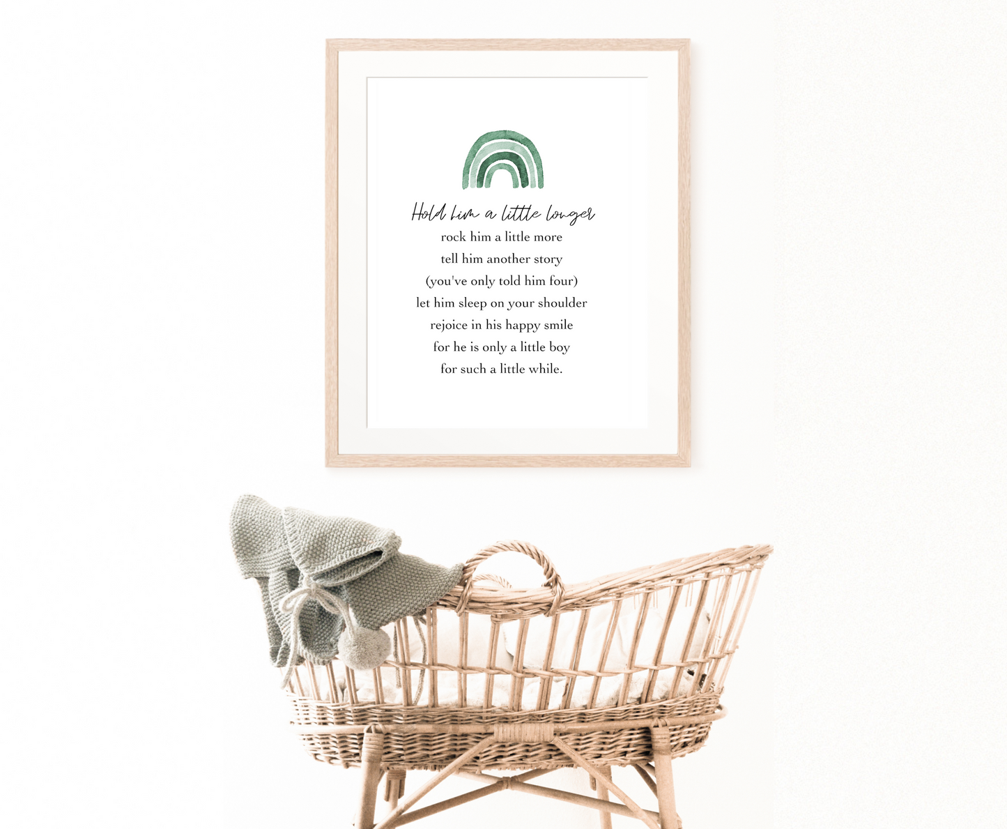 A picture showing a digital poster hung on the wall behind a cradle. The digital poster has different shades of green and blue rainbow, with a piece of writing that says: Hold him a little longer, rock him a little more, tell him another story, (you have only told him four), let him sleep on your shoulder, rejoice in his happy smile, for he is only a little boy, for such a little while.