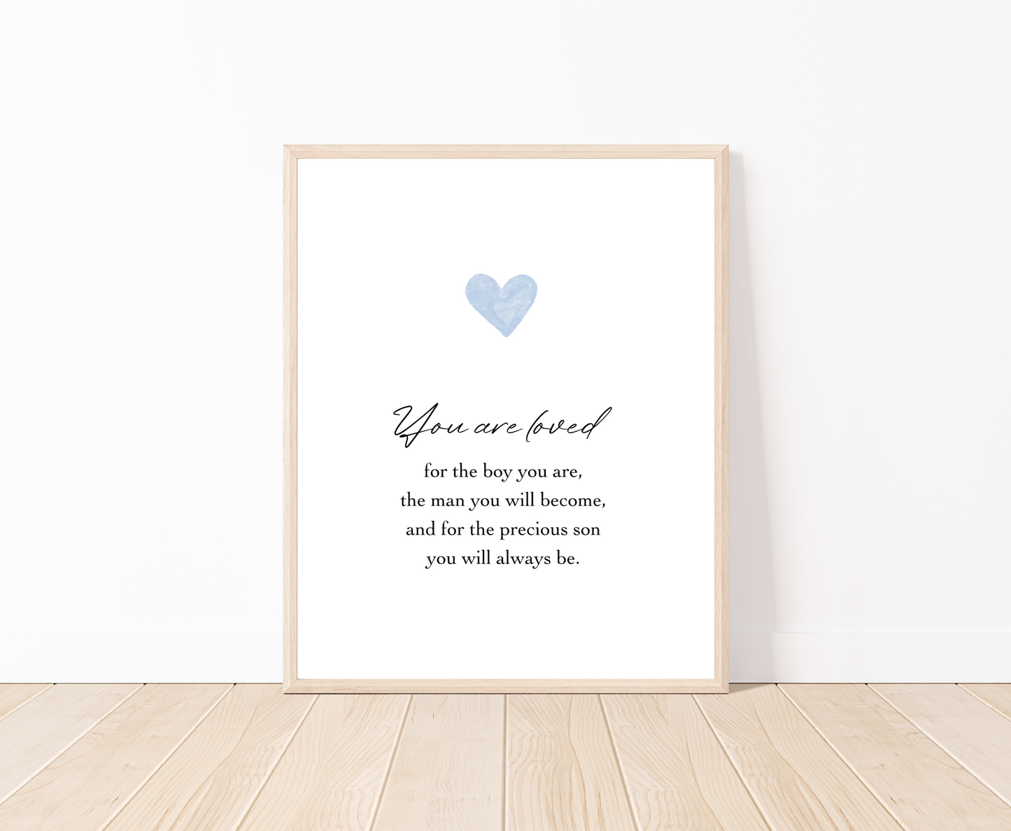 A digital poster is placed on a white wall and parquet flooring and has a blue heart at the top with a piece of writing that says: “You are loved for the boy you are, the man you will become, and for the precious son you will always be.”