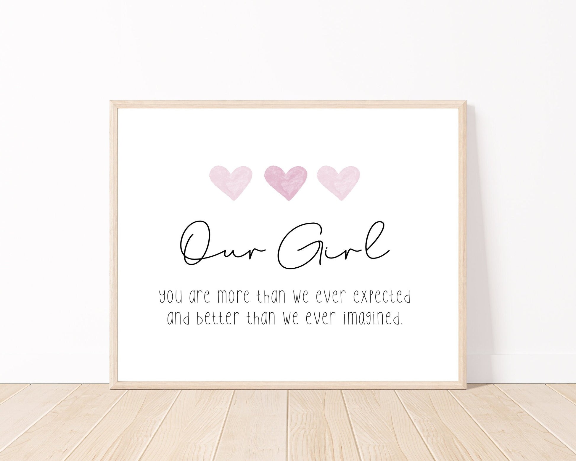 A little girl’s room digital print placed on a white wall and parquet flooring that has three pink hearts at the top, and a piece of writing that says: “Our girl, you are more than we ever expected and better than we ever imagined.”