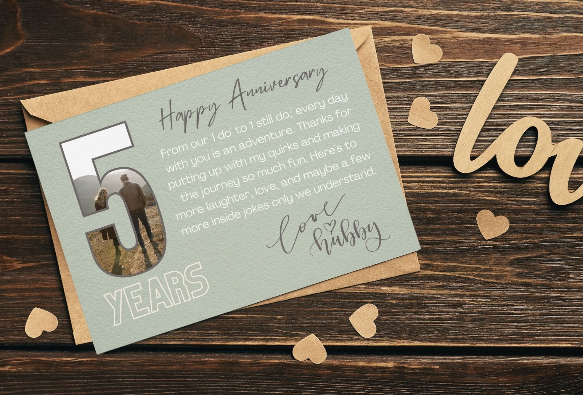 Happy anniversary greeting card with envelope on a dark wood table with brown heart cutouts.