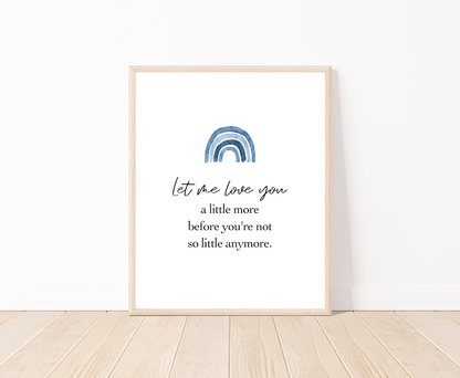 A digital poster placed on a white wall and parquet flooring that has a blue rainbow at the top, and a piece of writing that says: “Let me love you, a little more before you’re not so little anymore.”