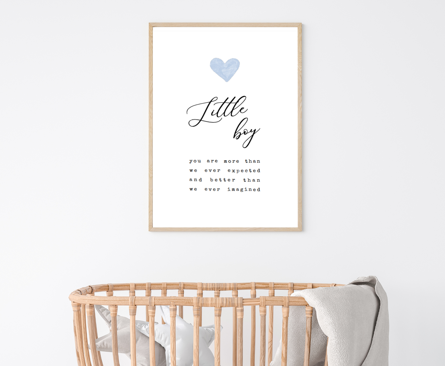 A digital print is hung above a baby’s cradle. The digital print has a blue heart at the top and a piece of writing that says: “Little boy, you are more than we ever expected and better than we ever imagined.”