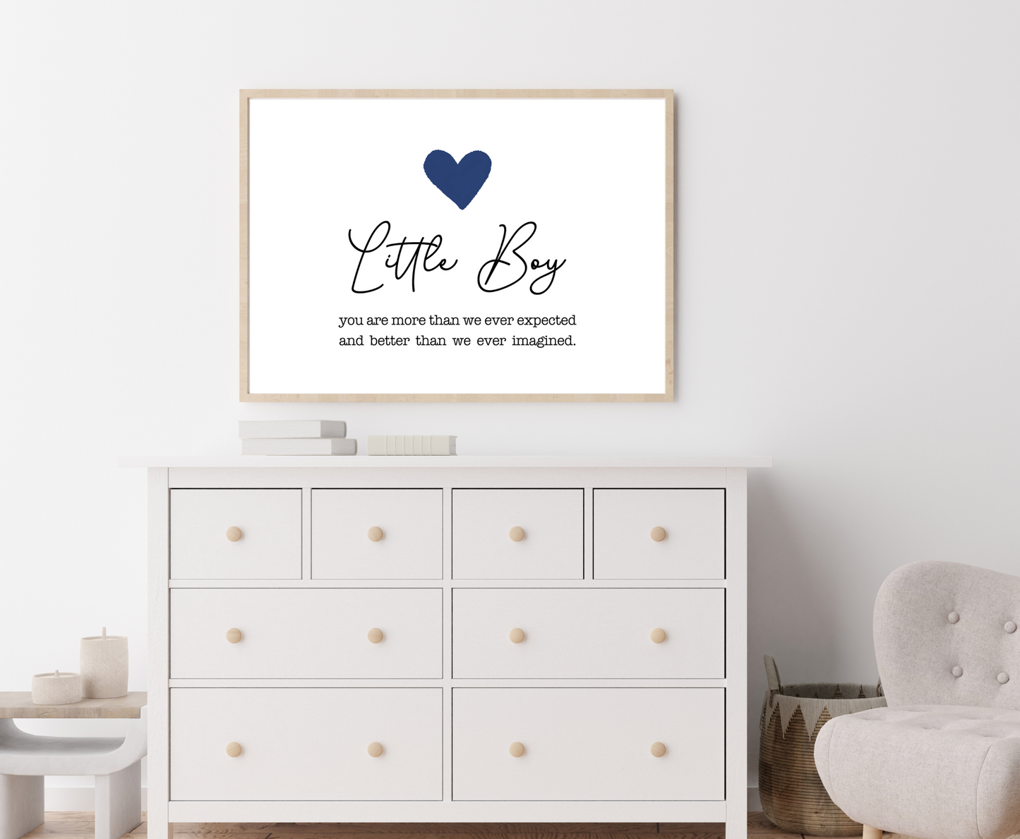 An image of a white dresser with a frame hanging on the wall behind it. The frame displays a dark blue heart with a piece of writing below that says: Little boy, you are more than we ever expected and better than we ever imagined.