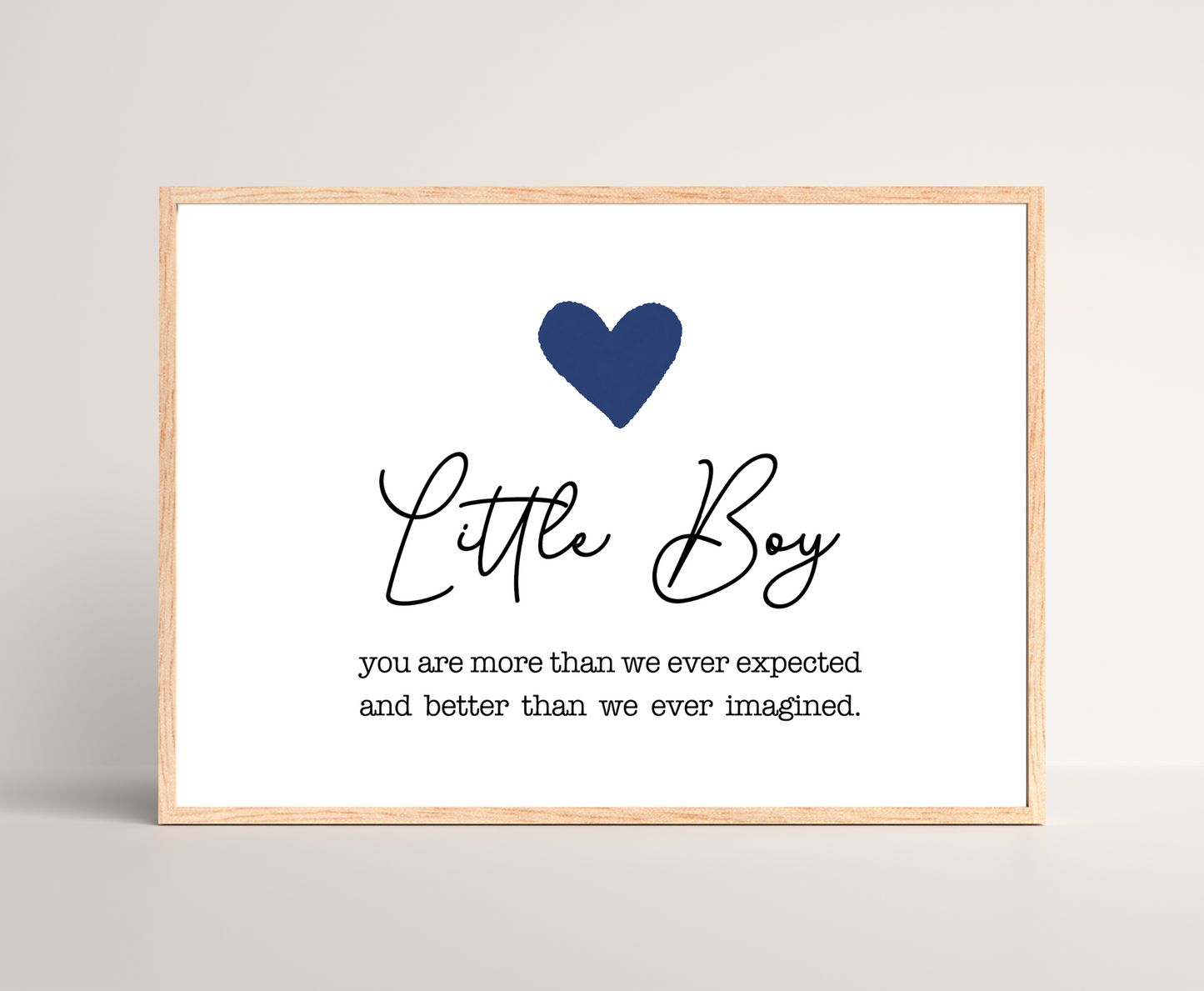 A frame displaying a dark blue heart with a piece of writing below that says: Little boy, you are more than we ever expected and better than we ever imagined.