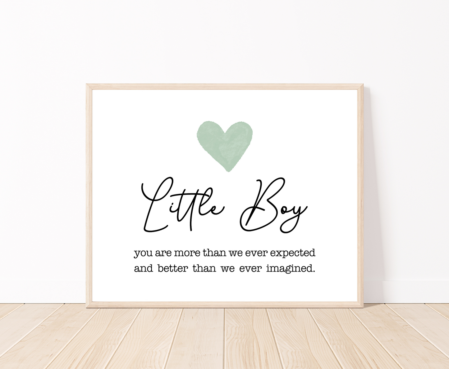 A frame displaying a baby green heart with a piece of writing below that says: you are more than we expected and better than we ever imagined. The frame is then placed on a parquet floor.