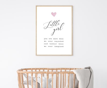 An image of a cradle with a frame hanging on the wall behind it. The frame displaying a digital graphic that has a pink heart and a piece of writing below that says: little girl you are more than we ever expected and better than we ever imagined. 