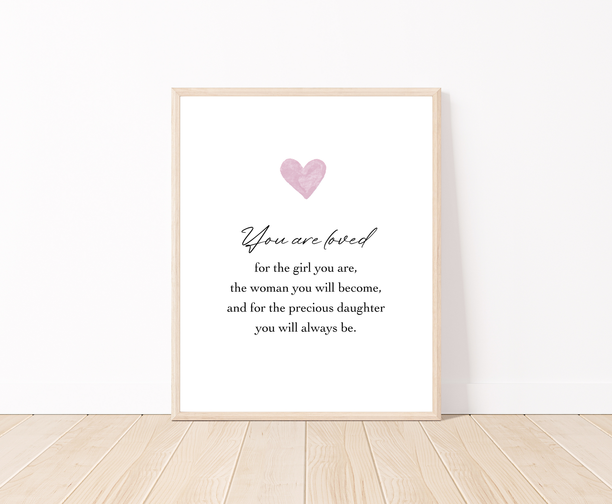 A digital poster is placed on a white wall and parquet flooring and has a pink heart at the top with a piece of writing that says: “You are loved for the girl you are, the woman you will become, and for the precious daughter you will always be.”