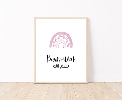 A digital print placed on a white wall and parquet flooring showing a pink rainbow with a piece of writing below that says: “Bismillah”.