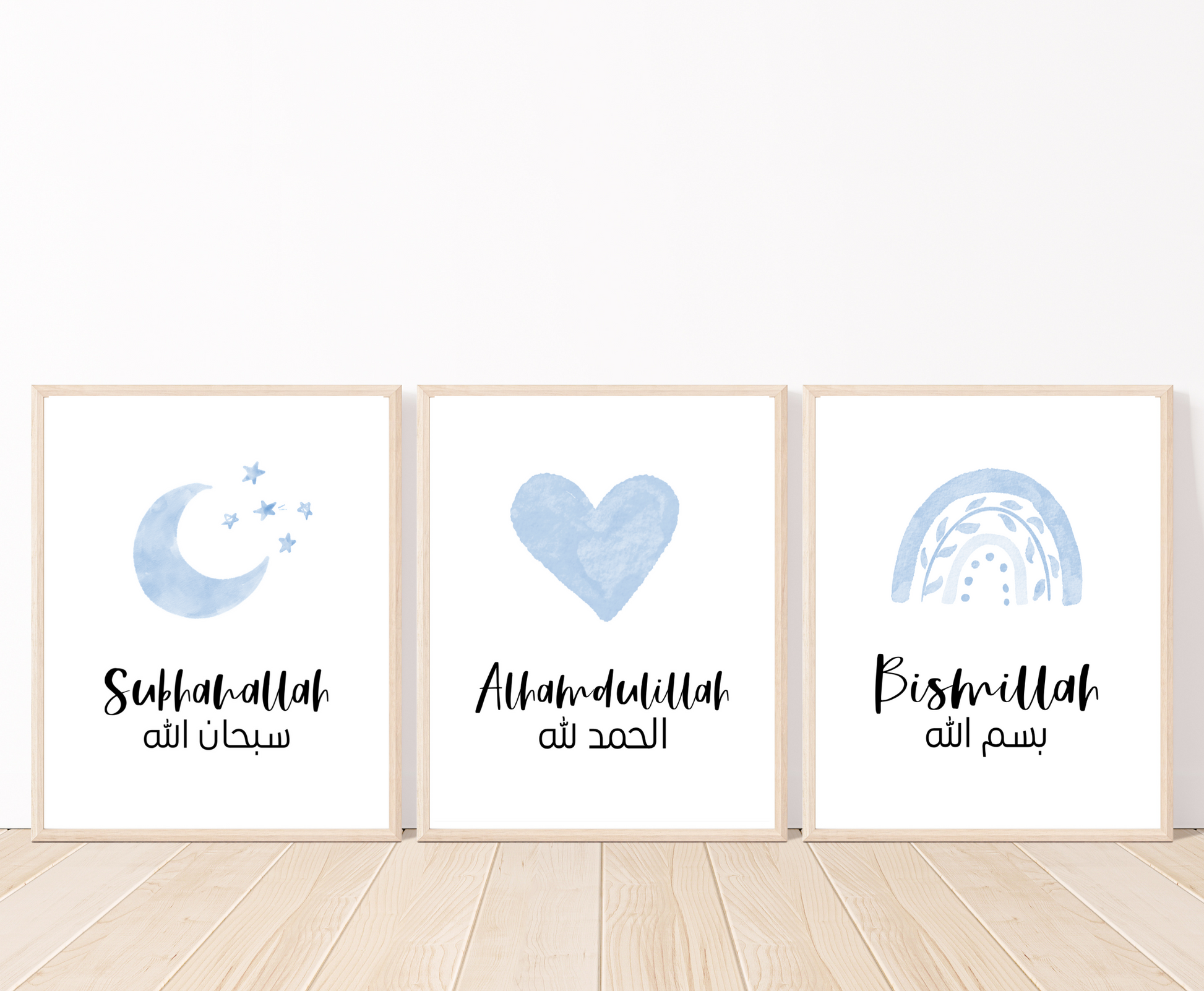 Three frames showing graphics for a baby boy’s room that are placed on a white wall and parquet flooring. The first one shows a small blue moon and three small stars with a piece of writing below that says: “Subhanallah”. The middle graphic shows a blue heart with a piece of writing below that says: “Alhamdulillah”. The last one shows a blue rainbow with a piece of writing below that says: “Bismillah”.
