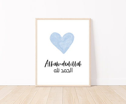 A digital print placed on a white wall and parquet flooring showing a blue heart with a piece of writing below that says: “Alhamdulillah”.