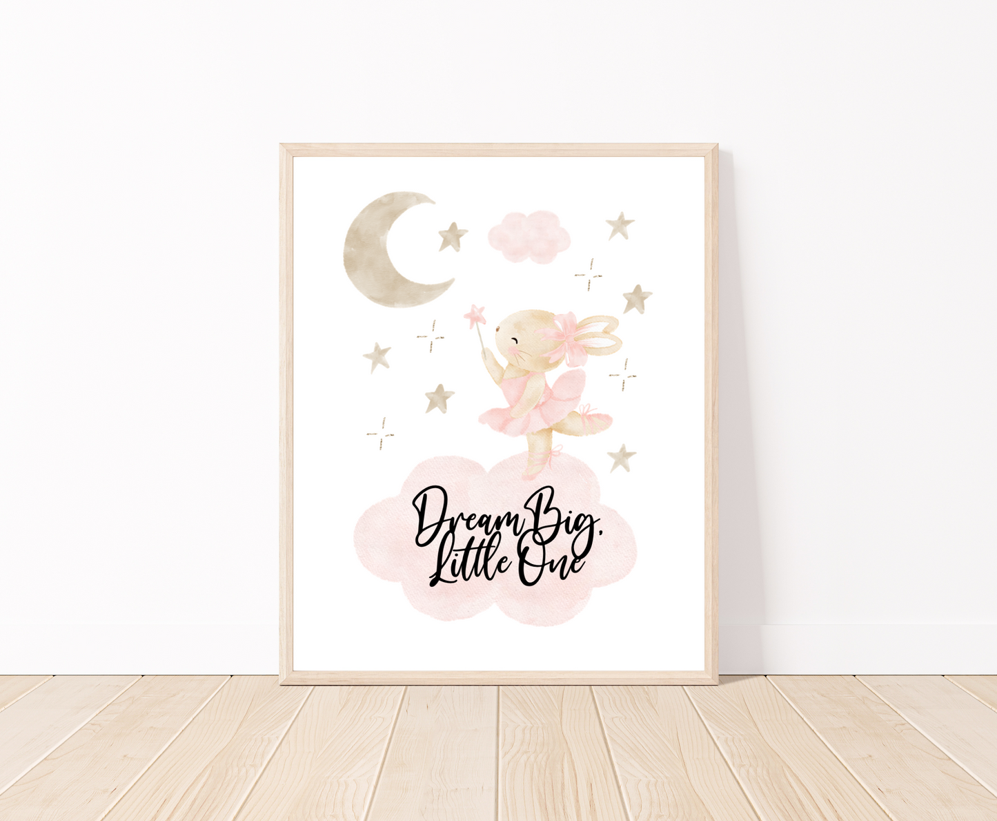 A little girl’s room graphic placed on a white wall and parquet flooring. It shows a grey-pinkish crescent with a brown teddy rabbit wearing a pink bow, with a few tiny grey-pinkish stars beside it and two pinkish clouds. It also includes a piece of writing that says “Dream Big Little One”.