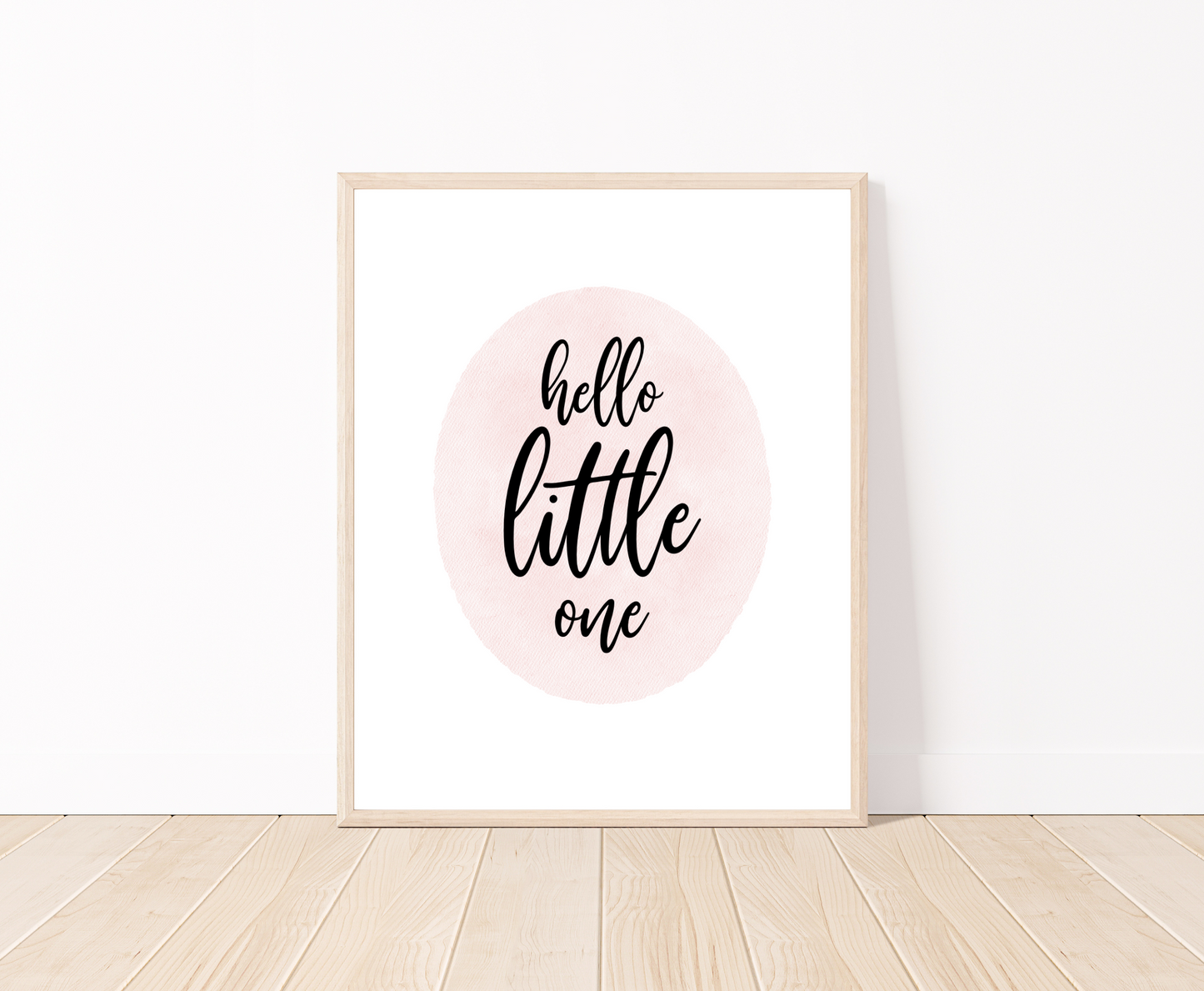 A digital print placed on a white wall and parquet flooring showing a pink oval shape that says “Hello little one”