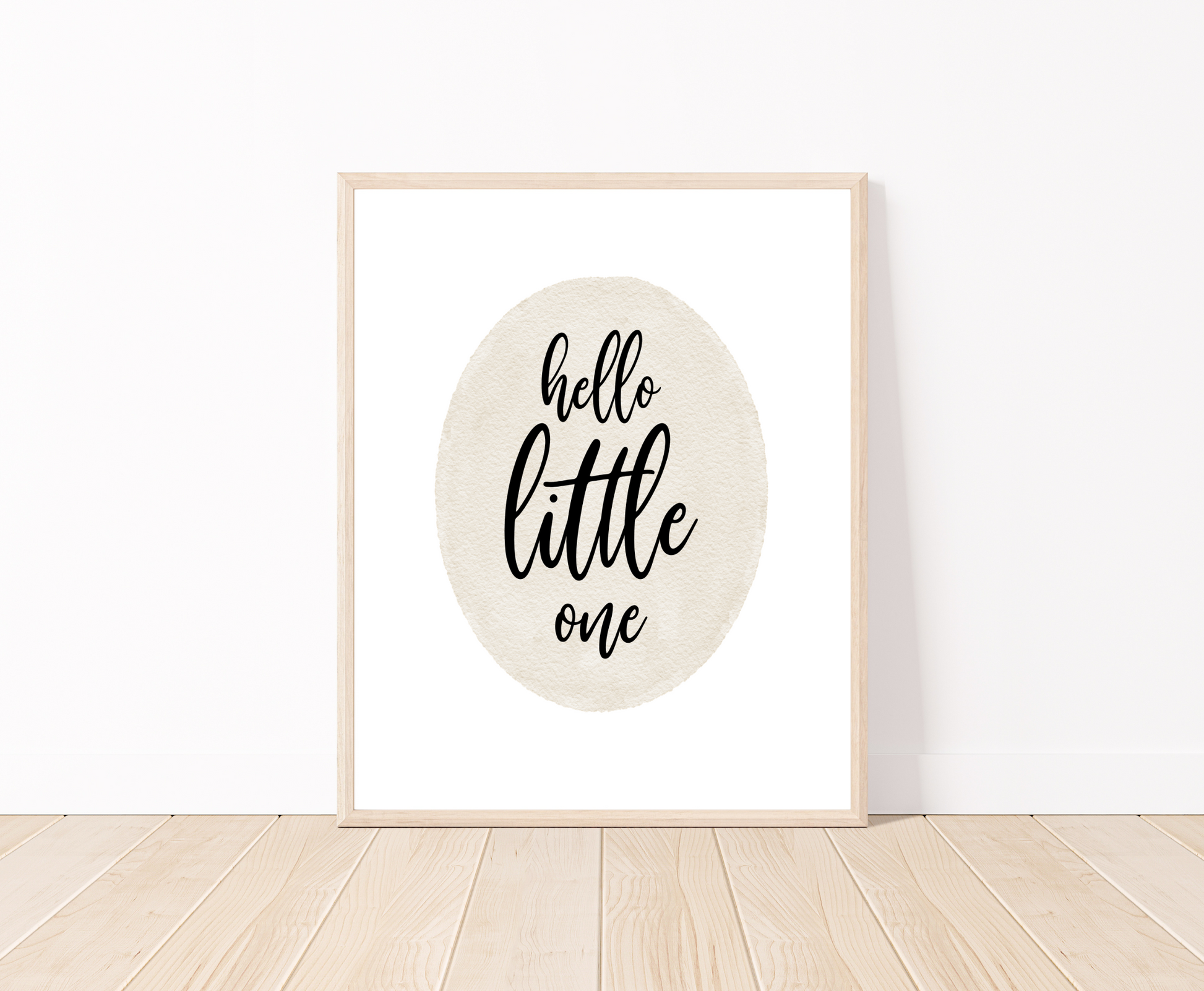 A digital print placed on a white wall and parquet flooring showing a grey oval shape that says “Hello little one”