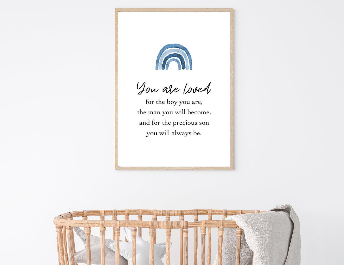 A picture showing a digital poster hung on the wall above a cradle. The digital poster has a blue rainbow, with a piece of writing that says: “You are loved for the boy you are, the man you will become, and for the precious son you will always be.”
