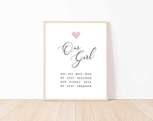 A little girl’s room digital print placed on a white wall and parquet flooring that has a pink heart at the top: one pink and two light brown, and a piece of writing that says: “Our girl, you are more than we ever expected and better than we ever imagined.”