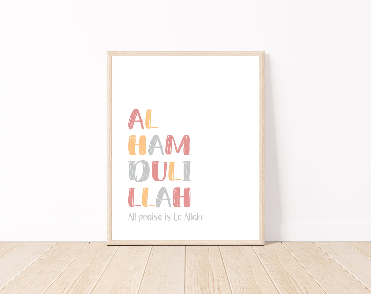 A digital print is placed on a white wall and parquet flooring. It includes “Alhamdulillah, all praise to Allah” written in multi-colored letters with a white background.