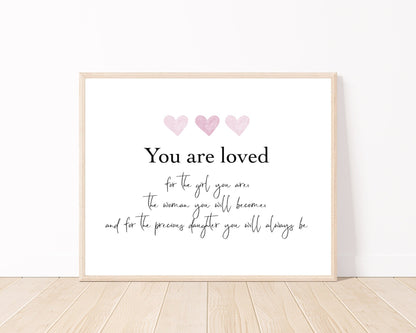 A little girl’s graphic showing three baby pink and beige hearts with a piece of writing below that says: You are loved, for the girl you are, the woman you will become, and for the precious daughter you will always be.