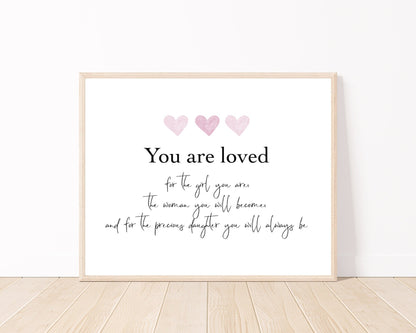 A little girl’s graphic showing three baby pink hearts with a piece of writing below that says: You are loved, for the girl you are, the woman you will become, and for the precious daughter you will always be.