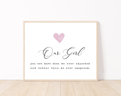 A little girl’s room digital print placed on a white wall and parquet flooring that has a pink heart at the top, and a piece of writing that says: “Our girl, you are more than we ever expected and better than we ever imagined.”