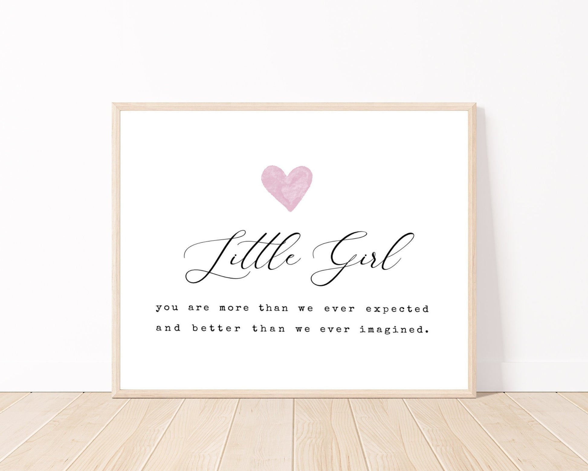 A little girl’s room horizontal digital print placed on a white wall and parquet flooring that has a pink heart at the top, and a piece of writing that says: “Little girl, you are more than we ever expected and better than we ever imagined.”