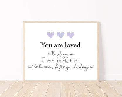 A little girl’s graphic showing three purple blue hearts with a piece of writing below that says: You are loved, for the girl you are, the woman you will become, and for the precious daughter you will always be.