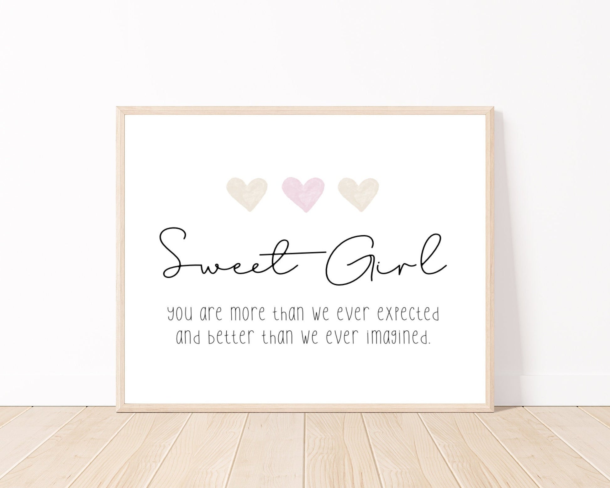 A little girl’s room digital print placed on a white wall and parquet flooring that has three hearts at the top, and a piece of writing that says: “Sweet girl, you are more than we ever expected and better than we ever imagined.”