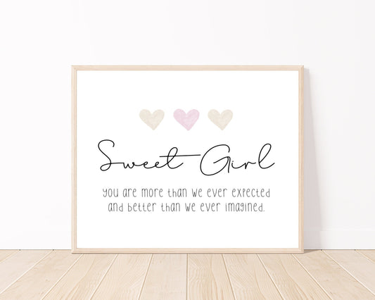 A little girl’s room digital print placed on a white wall and parquet flooring that has three hearts at the top, and a piece of writing that says: “Sweet girl, you are more than we ever expected and better than we ever imagined.”