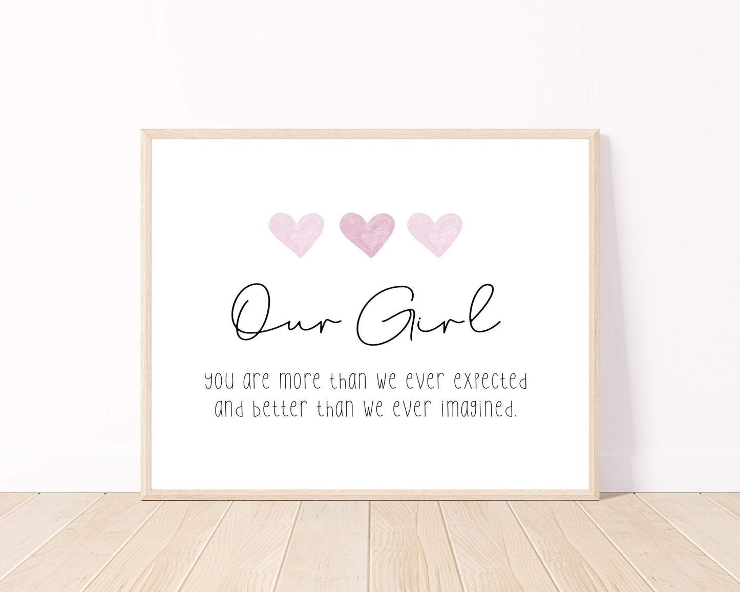 A little girl’s room digital print placed on a white wall and parquet flooring that has three pink hearts at the top, and a piece of writing that says: “Our girl, you are more than we ever expected and better than we ever imagined.”
