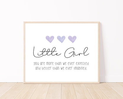 A little girl’s room digital print placed on a white wall and parquet flooring that has three purple hearts at the top, and a piece of writing that says: “Little girl, you are more than we ever expected and better than we ever imagined.”