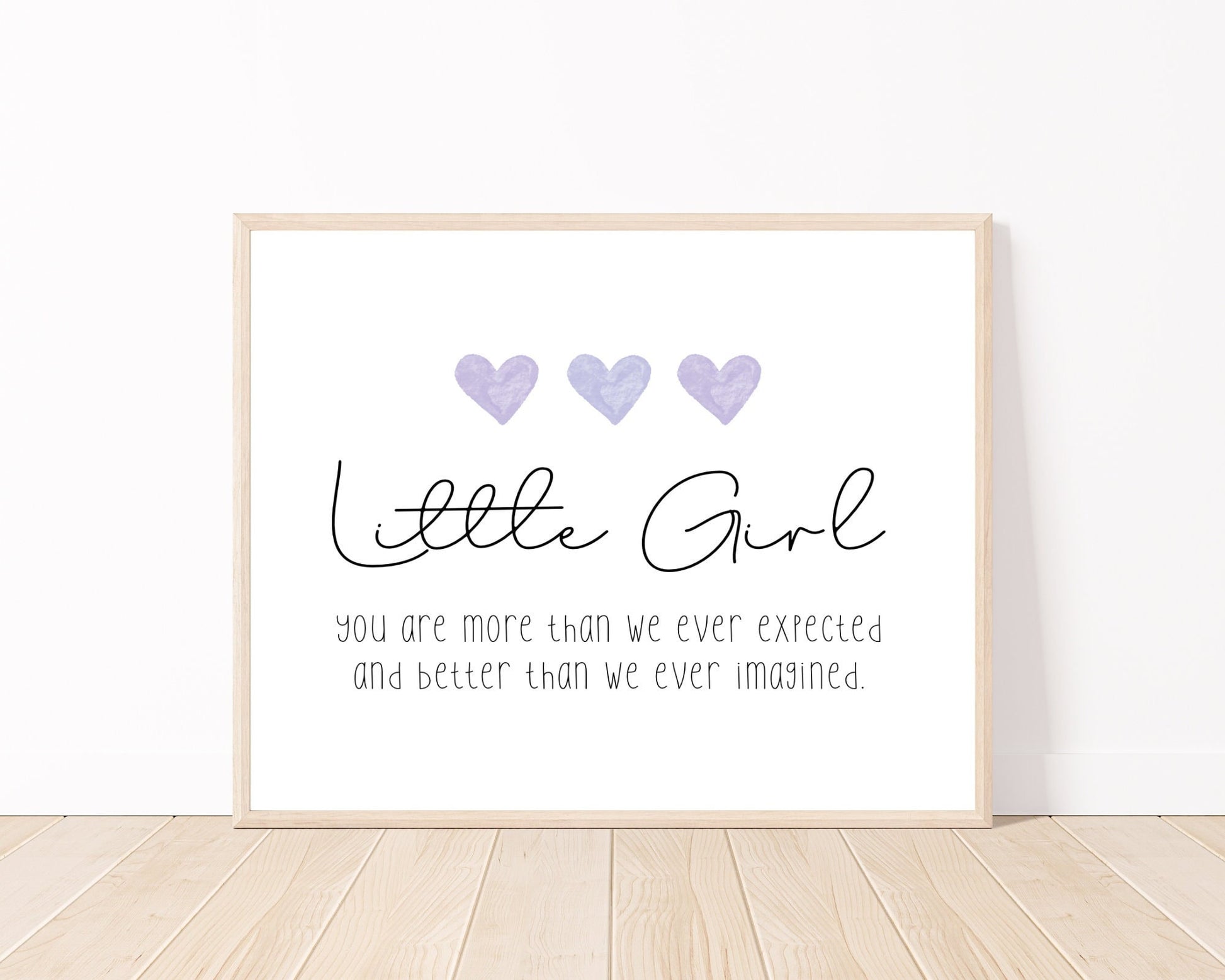 A little girl’s room digital print placed on a white wall and parquet flooring that has three purple hearts at the top, and a piece of writing that says: “Little girl, you are more than we ever expected and better than we ever imagined.”