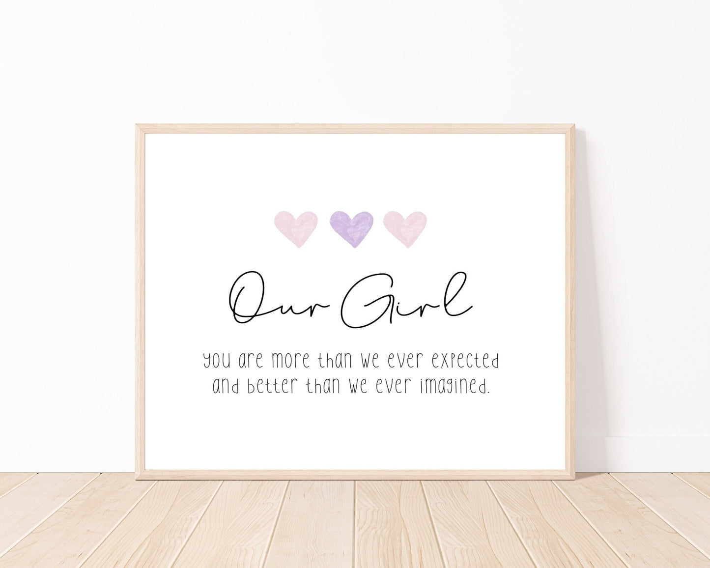 A little girl’s room digital print placed on a white wall and parquet flooring that has three hearts at the top, and a piece of writing that says: “Our girl, you are more than we ever expected and better than we ever imagined.”