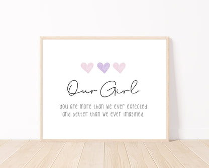 A little girl’s graphic showing three baby pink and purple hearts with a piece of writing below that says: Our girl, you are more than we ever expected, and better than we ever imagined.